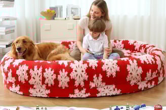 a woman and a dog  sitting on a  human size dog bed
