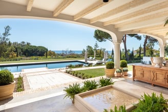 View from the shaded porch across the pool, with the Mediterranean Sea visible in the background.