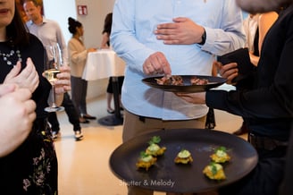 Ein Kellner verteilt Hors d'oeuvre auf schwarzen Tellern.