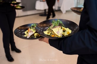 Kellner trägt Teller mit einem Fisch-Hauptgericht.