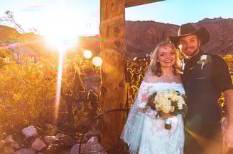 a man and woman in cowboy attire standing in front of a wooden structure