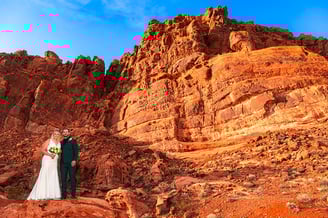 a bride and groom standing on a rocky mountain