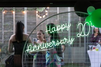 SweetAz Co. circle backdrop with a glowing green ‘Happy 20th Anniversary’ neon sign at a vow renewal event in Redland Bay, wi