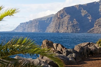 Vista de la costa rocosa de Tenerife con montañas y mar, un entorno natural ideal para terapias de bienestar y relajación emo