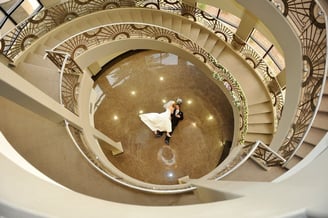 a bride and groom walking down a spiral staircase