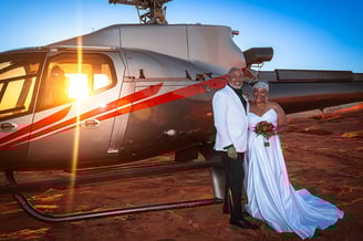 a man and woman standing in front of a helicopter