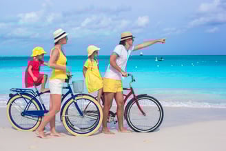 Family travelers riding bicycles on a tropical beach