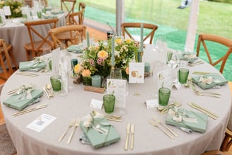 a table with a table setting with spring flowers and green glasses