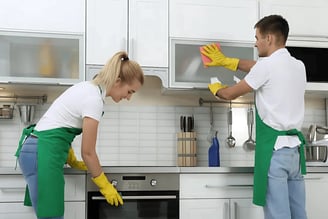 a man and woman cleaning a kitchen
