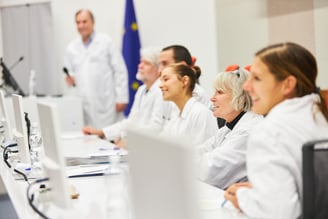 a group of people sitting at a table with laptops