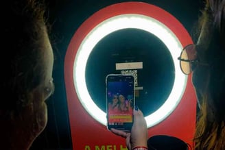 Pessoas tirando foto num totem de fotos e compartilhando nas redes sociais