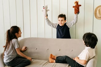 Children laughing whilst playing with sock puppets.