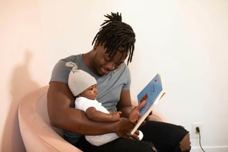 A young father reading a children's picture book to a child.