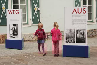 Besucher erkunden die Außenanlage der mobilen Ausstellung "Aus weg los!".