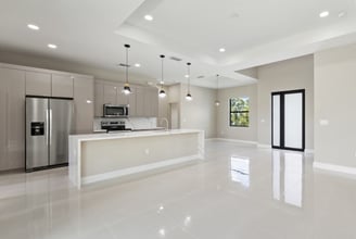 Open kitchen and living floor plan featuring bege cabinets