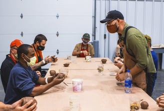 Image of an instructor leading a clay project in front of our Veteran class.