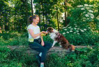 Antonia sitzt mit Hund auf Baumstamm – kleine Übungen im Mini Workshop mit Fokus auf Beziehung