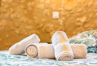 Plan serré sur des serviettes pliées avec soin, posées sur un lit dans une chambre d’hôtes