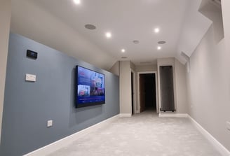 a large flat screen tv mounted on a wall with ceiling audio speakers. Brixton