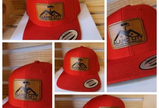 Red snapback hats with custom laser-engraved leather patches featuring Alamo City Painting LLC logo