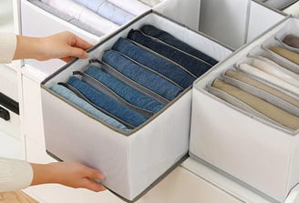 a person holding a drawer full of folded folded folded fabric
