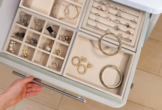 a person holding a drawer full of jewelry