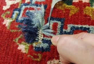restauratore riannodando un tappeto nella ricostruzione di un buco