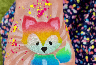 Rainbow fox airbrush tattoo on a child’s hand.