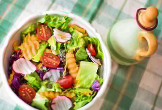 a bowl of salad with tomatoes and dressing dressing