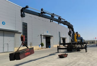Zorylift SQZ300A.5: Black 15T knuckle boom (truck/lorry) crane operating, lifts 500kg test weight outside factory.