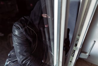 man in mask breaking into home through an unlocked window