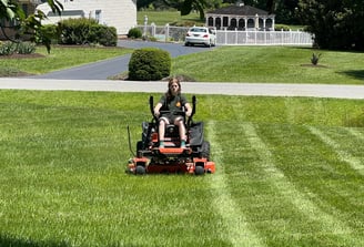 a man riding on a lawn mower in a yard