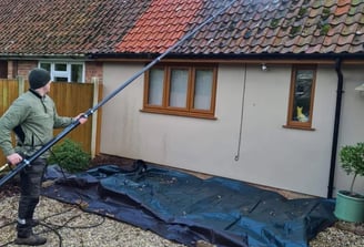 a professional roofer removing moss from a London property in need of a roof clean