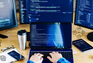 a person sitting at a desk with a laptop and a phone developing software