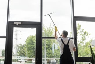 a man cleaning a window with a broom and a broom