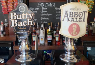 two beer taps with beer on a bar