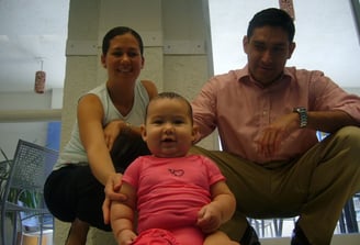 a man and woman sitting on a couch with a baby