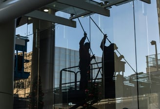 Persona limpiando un vidrio de un edificio.