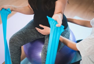 a pregnant woman is sitting on a yoga ball