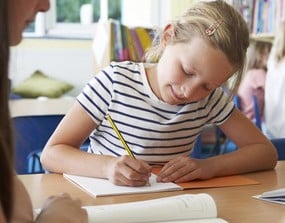 a girl is sitting at a table with a pencil and a pencil