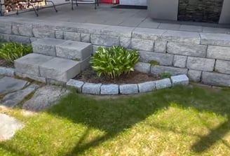 grey brick patio on the rear of a house with steps made of stone with manicured lawn