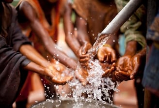 Hands collecting clean water from a community well in rural Africa.