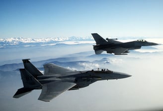 two jets are flying in the sky above the clouds