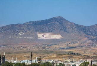 north cyprus's flag flying over a mountain range with a flag