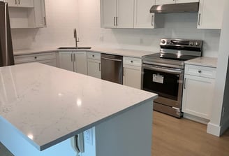 L-shaped kitchen with white shaker cabinets, subway tile backsplash, and quartz island countertop — 