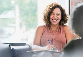 a woman sitting on a couch with a notebook and pen