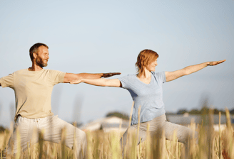 a man and woman doing yoga in the grass