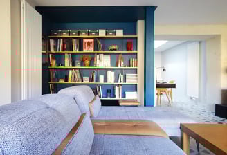 Salon TV avec fauteuil, méridienne et bibliothèque sur mesure en bois et métal. Ouverture sur bureau