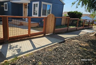 a hogwire fence with a redwood gate
