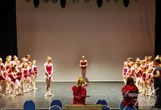 a group of young girls in red and white outfits on stage
